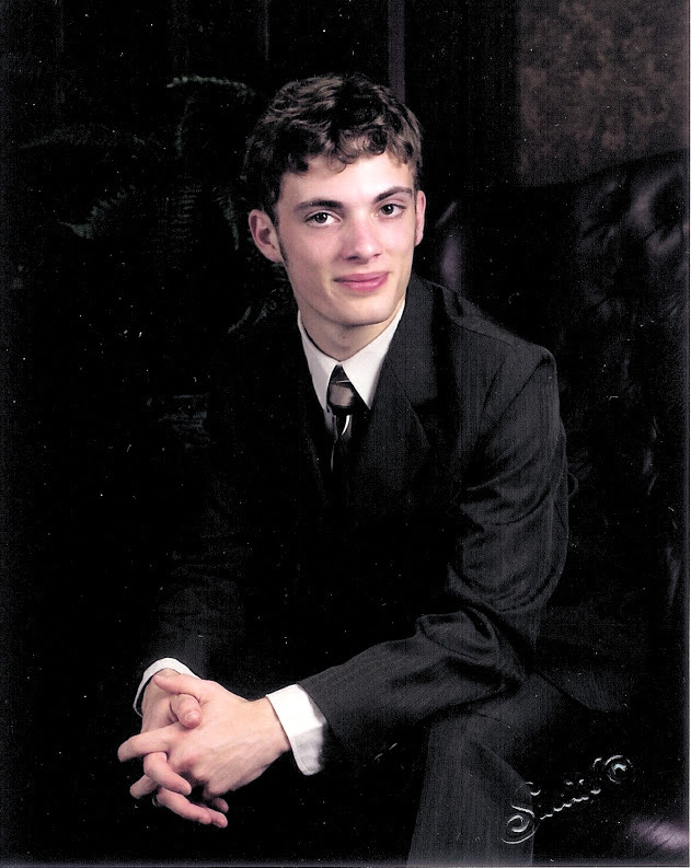 me in a dark green suit sitting in an office chair